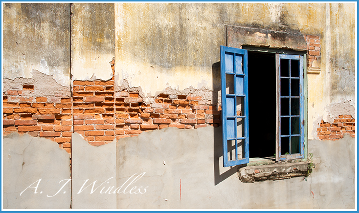 Window and wall of an abandoned house show the beauty of aging.