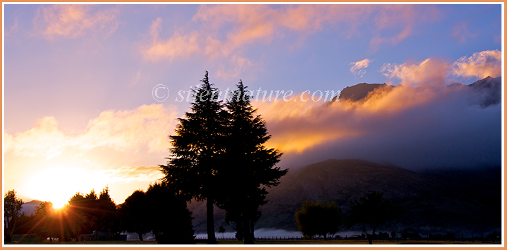 The sun rises below pink clouds near Queenstown