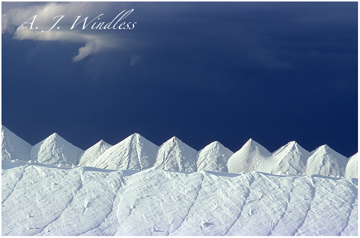 Deep blue storm clouds approach from behind piles of white salt near the Great Salt Lake.